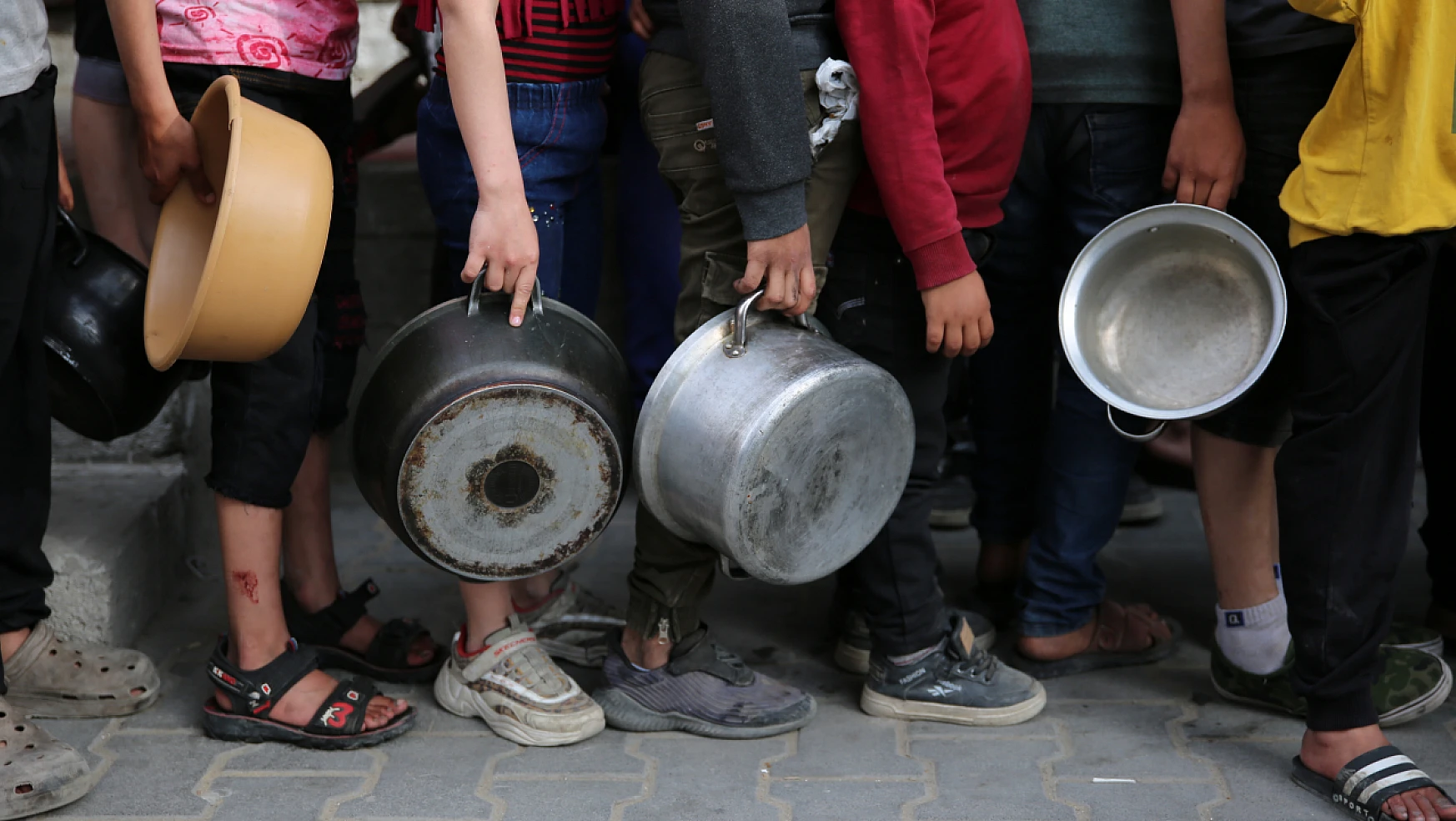 Gazzeli çocuklar bir kap sıcak yemek için uzun kuyruklarda bekliyor